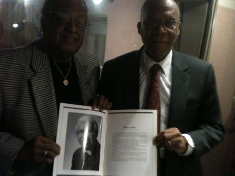 Ackneil Muldrow II, left, and Larry Gibson hold up a picture of "Little Willie" Adams in a program from a Baltimore Marketing Association event honoring him. Poorly lit iPhone photo credit: Lawrence Lanahan.